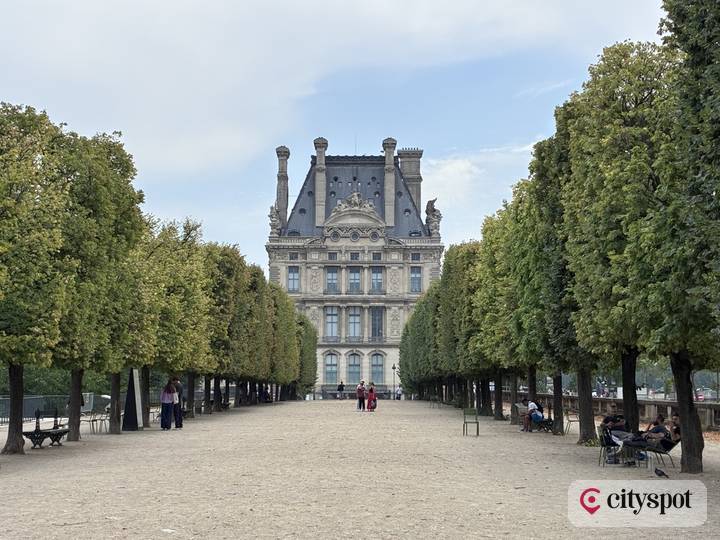 A tree-lined alley of the Tuileries Garden — with the Louvre at the end