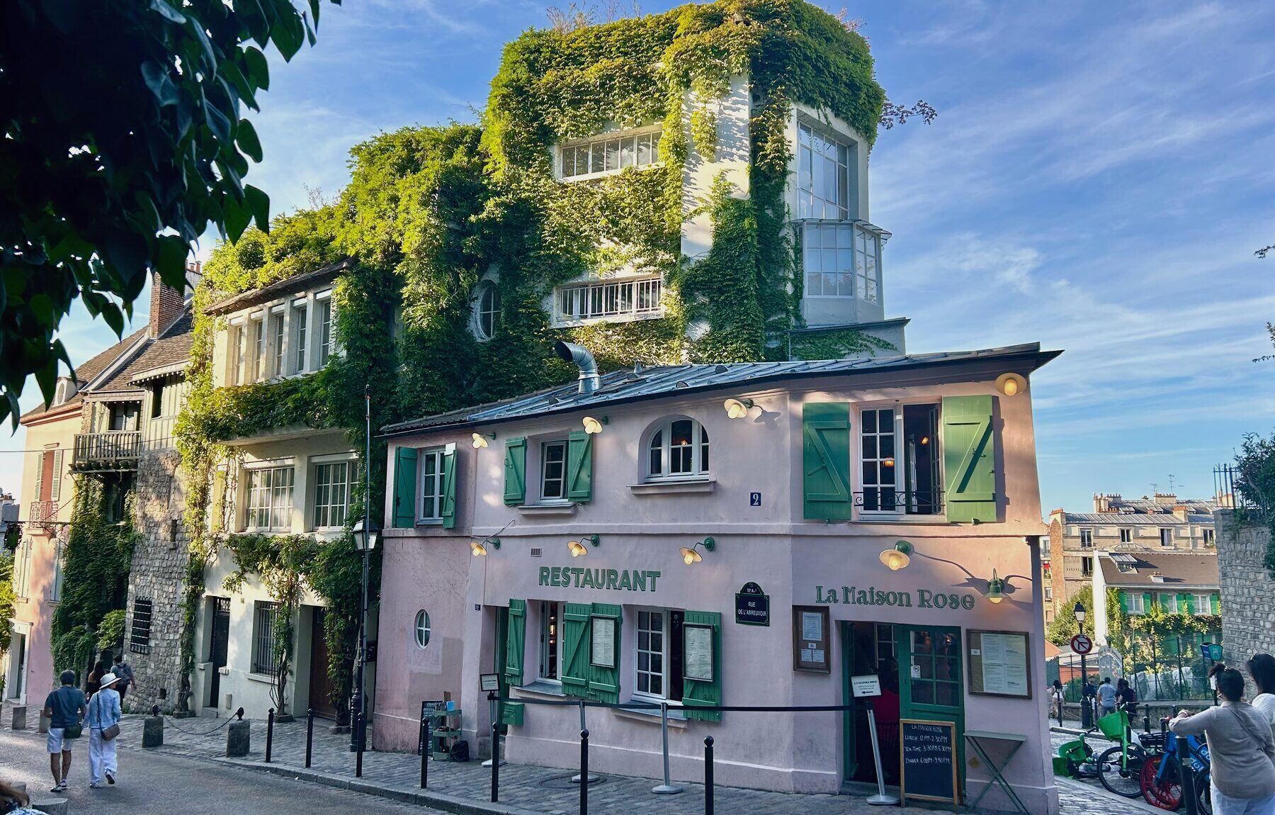 A pink restaurant covered in ivy on a Montmartre street corner